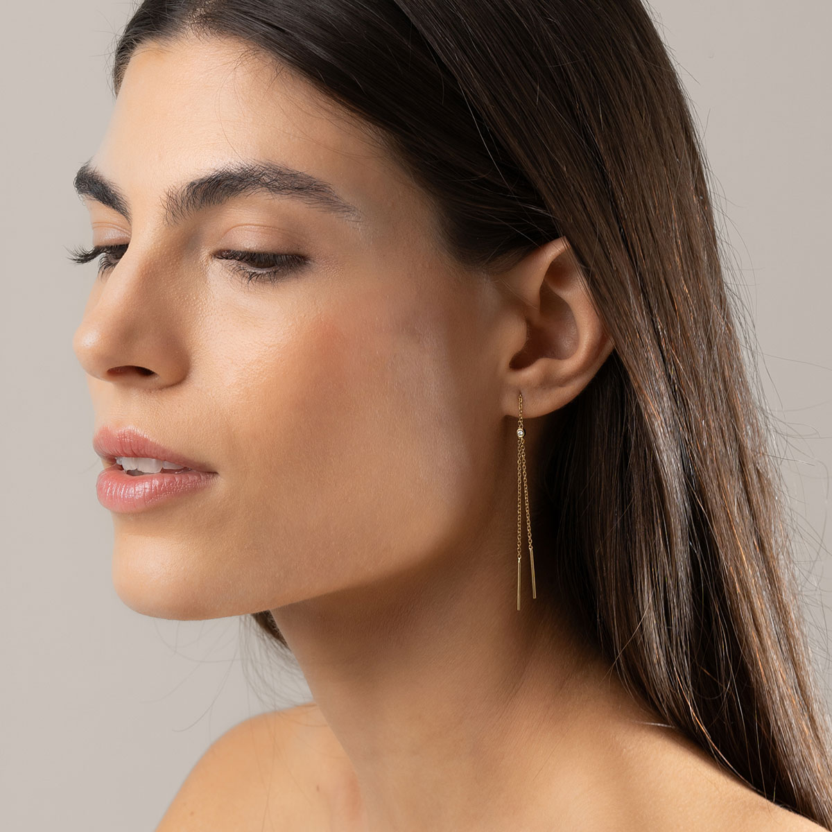 mulher usando brinco longo minimalista de corrente maleável feito à mão em ouro 18k com um diamante delicado