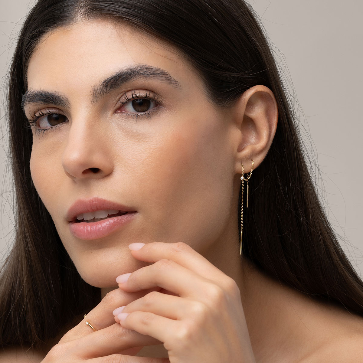 mulher usando brinco longo minimalista de corrente maleável feito à mão em ouro 18k com um diamante delicado