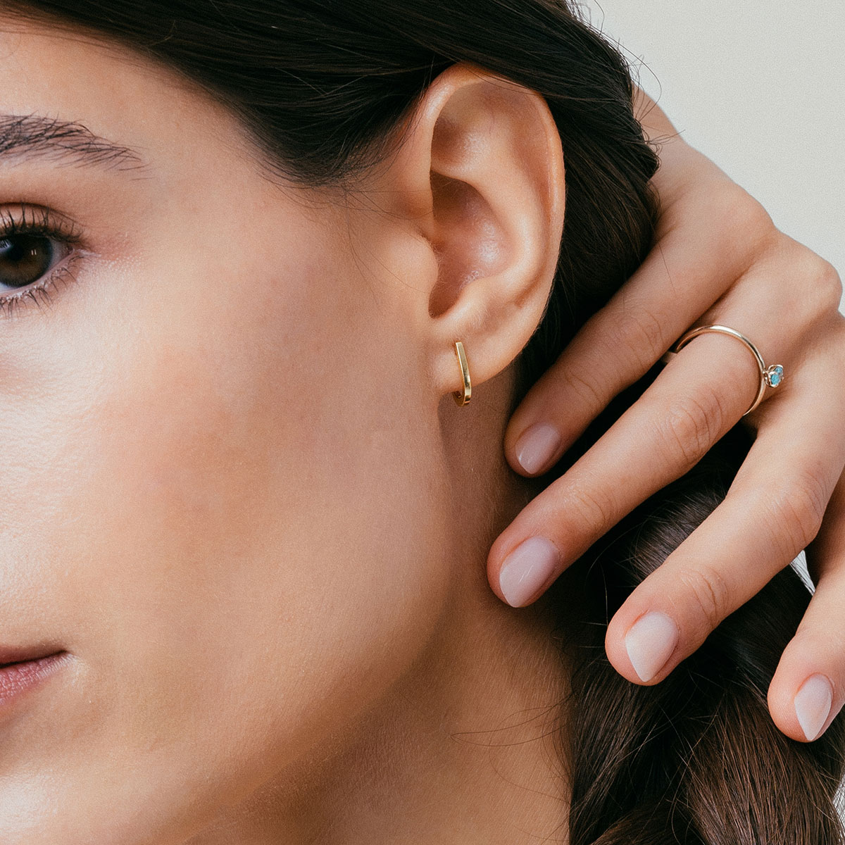 mulher usando brinco minimalista feito à mão em ouro 18k que abraça a orelha de forma delicada e sutil