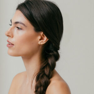 mulher usando brinco minimalista feito à mão em ouro 18k que abraça a orelha de forma delicada e sutil