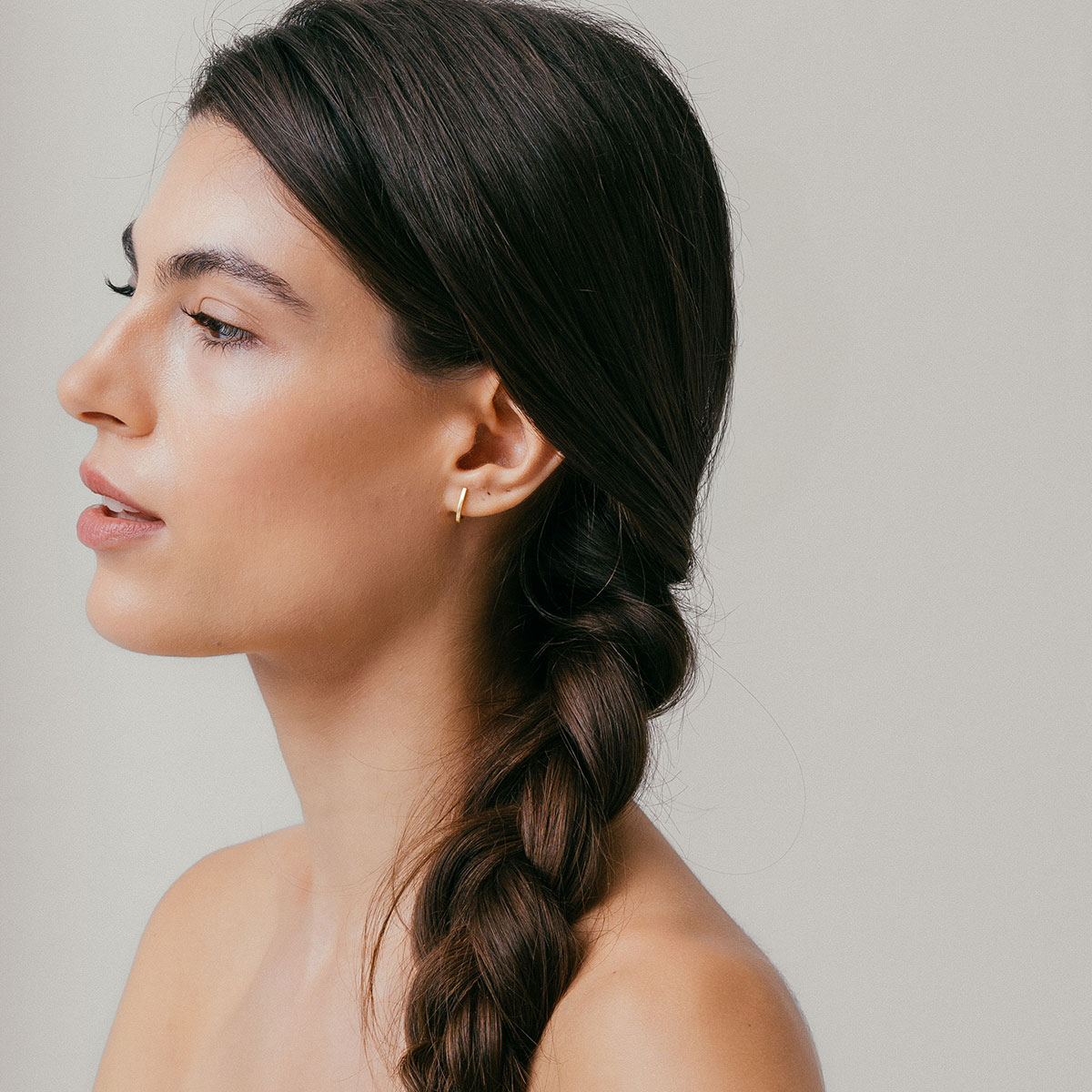 mulher usando brinco minimalista feito à mão em ouro 18k que abraça a orelha de forma delicada e sutil