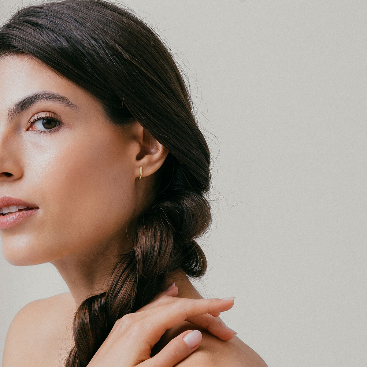 mulher usando brinco minimalista feito à mão em ouro 18k que abraça a orelha de forma delicada e sutil