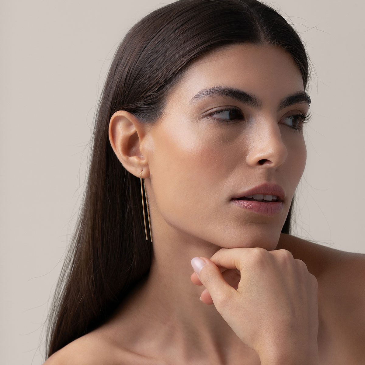 mulher usando brinco minimalista longo feito à mão com duas hastes e corrente maleável em ouro 18k