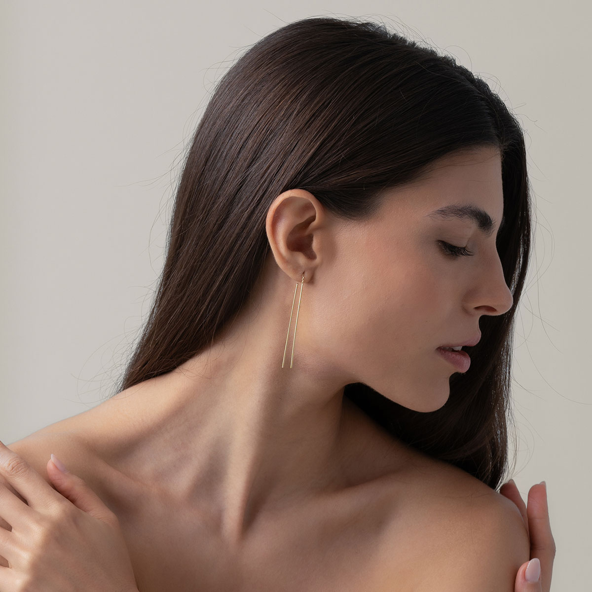 mulher usando brinco minimalista longo feito à mão com duas hastes e corrente maleável em ouro 18k