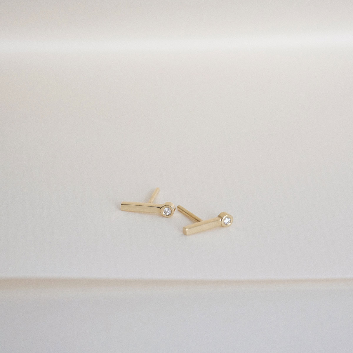 brinco delicado e minimalista feito à mão em ouro 18k em formato de palito com um diamante na ponta