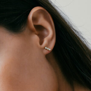 mulher usando brinco feito à mão em ouro 18k com três diamantes enfileirados