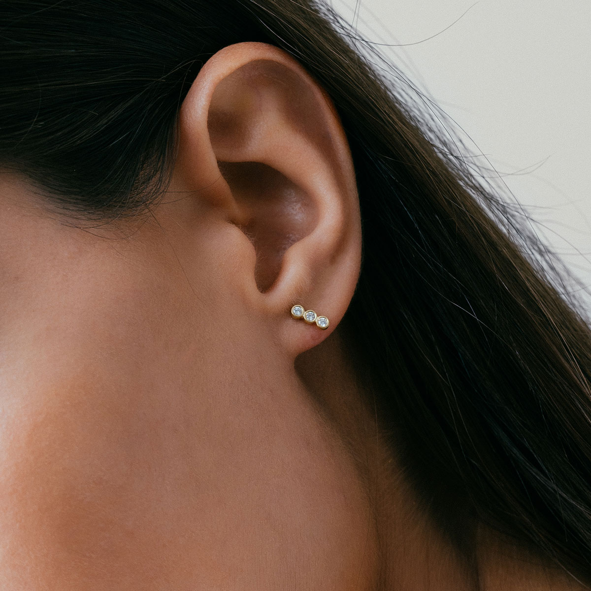 mulher usando brinco feito à mão em ouro 18k com três diamantes enfileirados