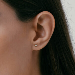 mulher usando brinco minimalista feito à mão em ouro 18k com diamante pequeno e delicado