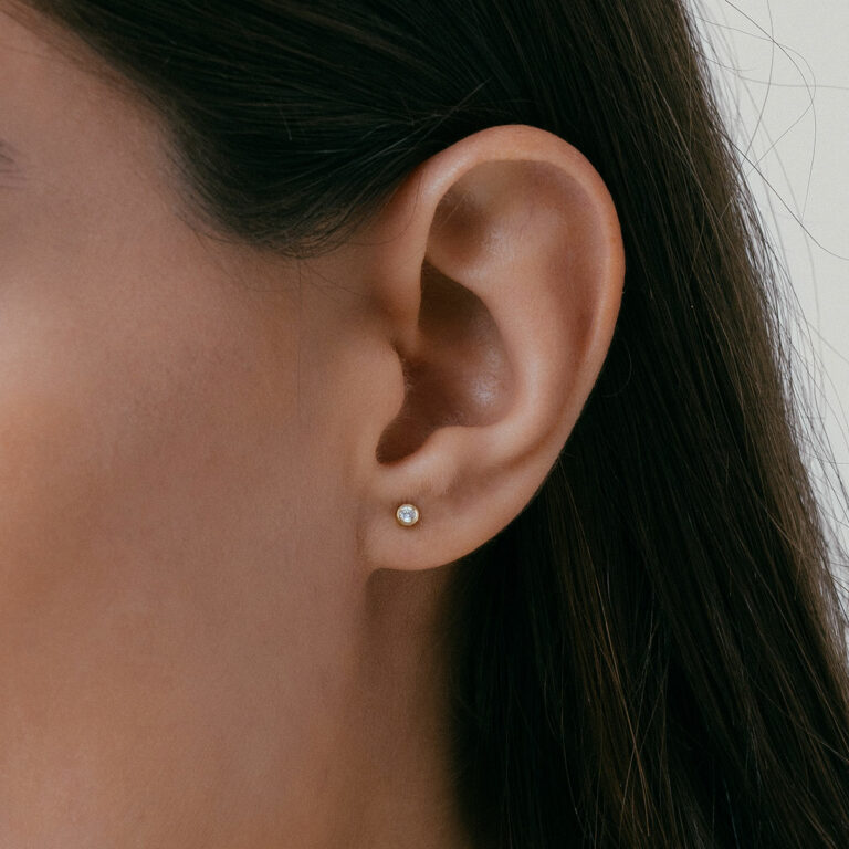 mulher usando brinco minimalista feito à mão em ouro 18k com diamante pequeno e delicado