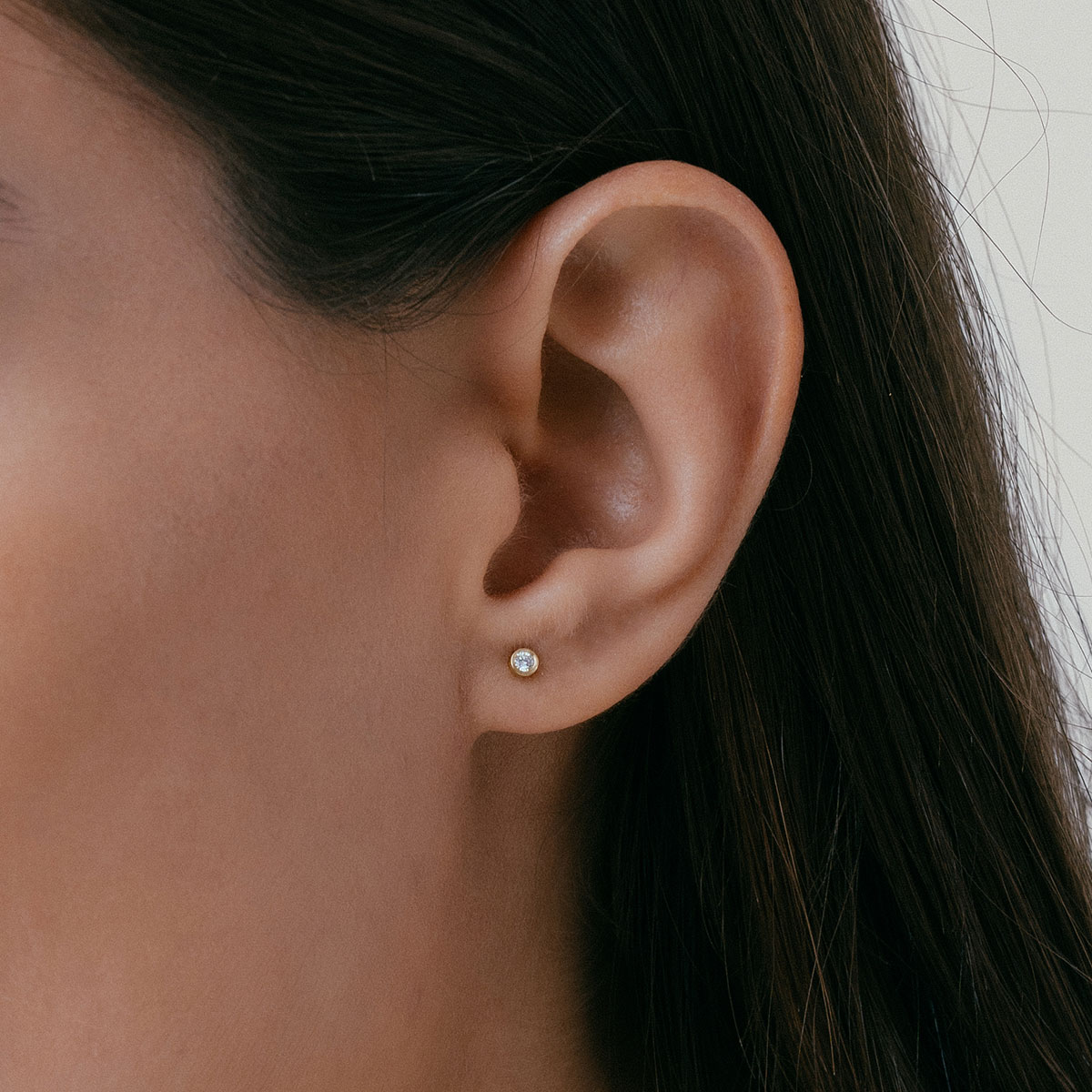 mulher usando brinco minimalista feito à mão em ouro 18k com diamante pequeno e delicado