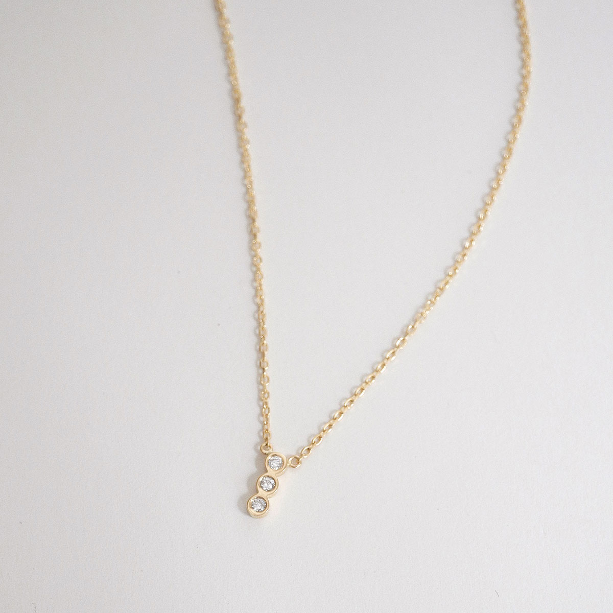 colar minimalista feito à mão em ouro 18k com três diamantes enfileirados verticalmente