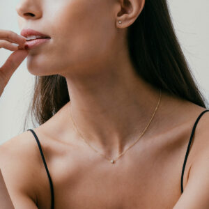 mulher usando colar minimalista e delicado feito à mão em ouro 18k com diamante ponto de luz central