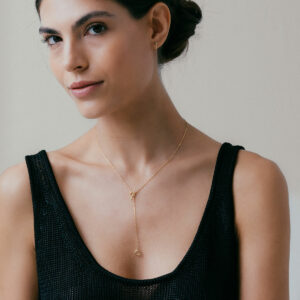 mulher de blusa preta usando colar minimalista de modelo gravatinha com fecho T feito à mão em ouro 18k