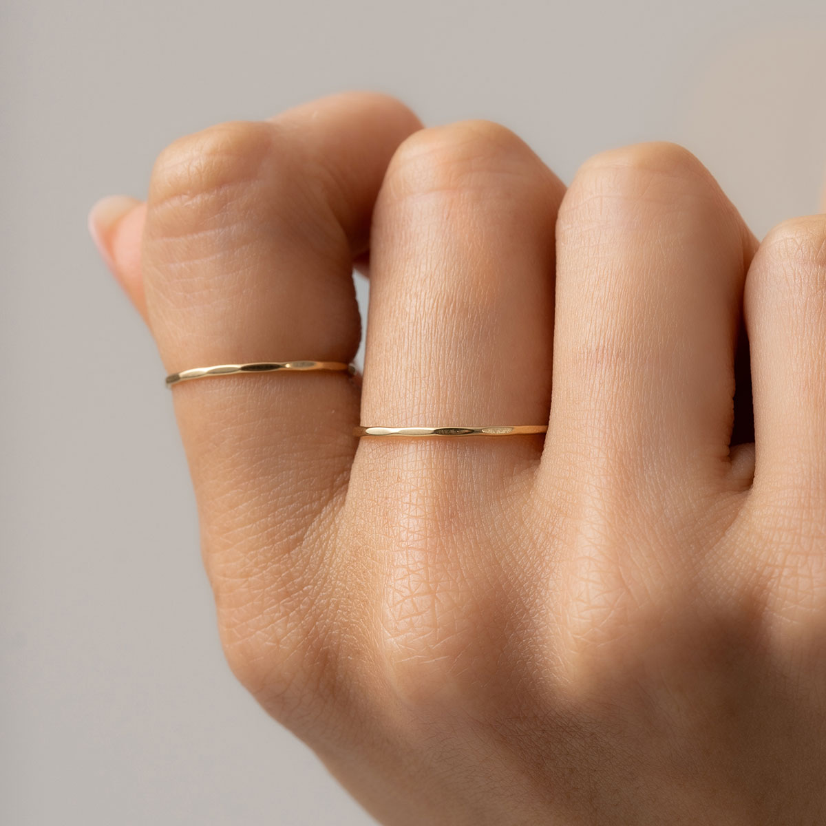 mulher usando conjunto de anéis de aro fino minimalista feitos à mão em ouro 18k com acabamento martelado