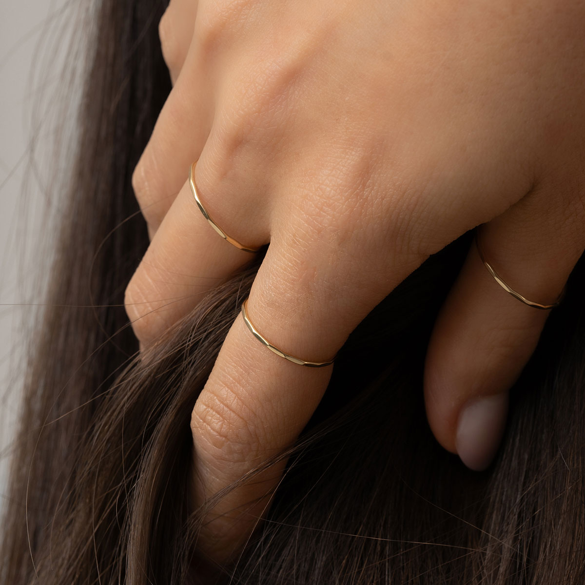 mulher usando conjunto de anéis de aro fino minimalista feitos à mão em ouro 18k com acabamento martelado