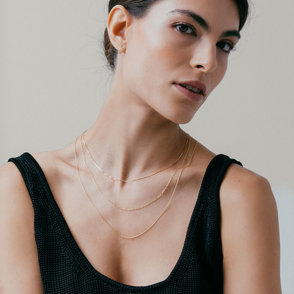 mulher de blusa preta usando colares de diferentes tamanhos e correntes em ouro 18k feitas à mão