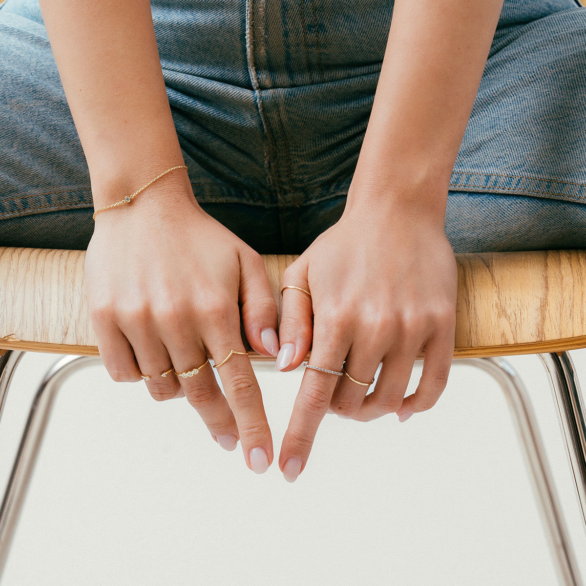 mulher usando anéis minimalistas feitos à mão em ouro 18k com diamantes