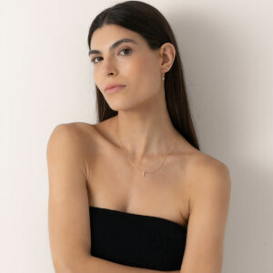 mulher usando colar e brinco feitos à mão em ouro 18k com diamantes enfileirados e brinco longo com apenas um diamante