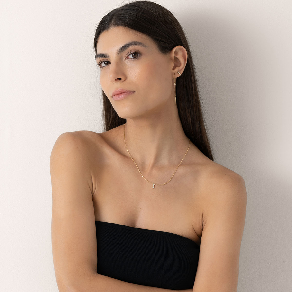 mulher usando colar e brinco feitos à mão em ouro 18k com diamantes enfileirados e brinco longo com apenas um diamante