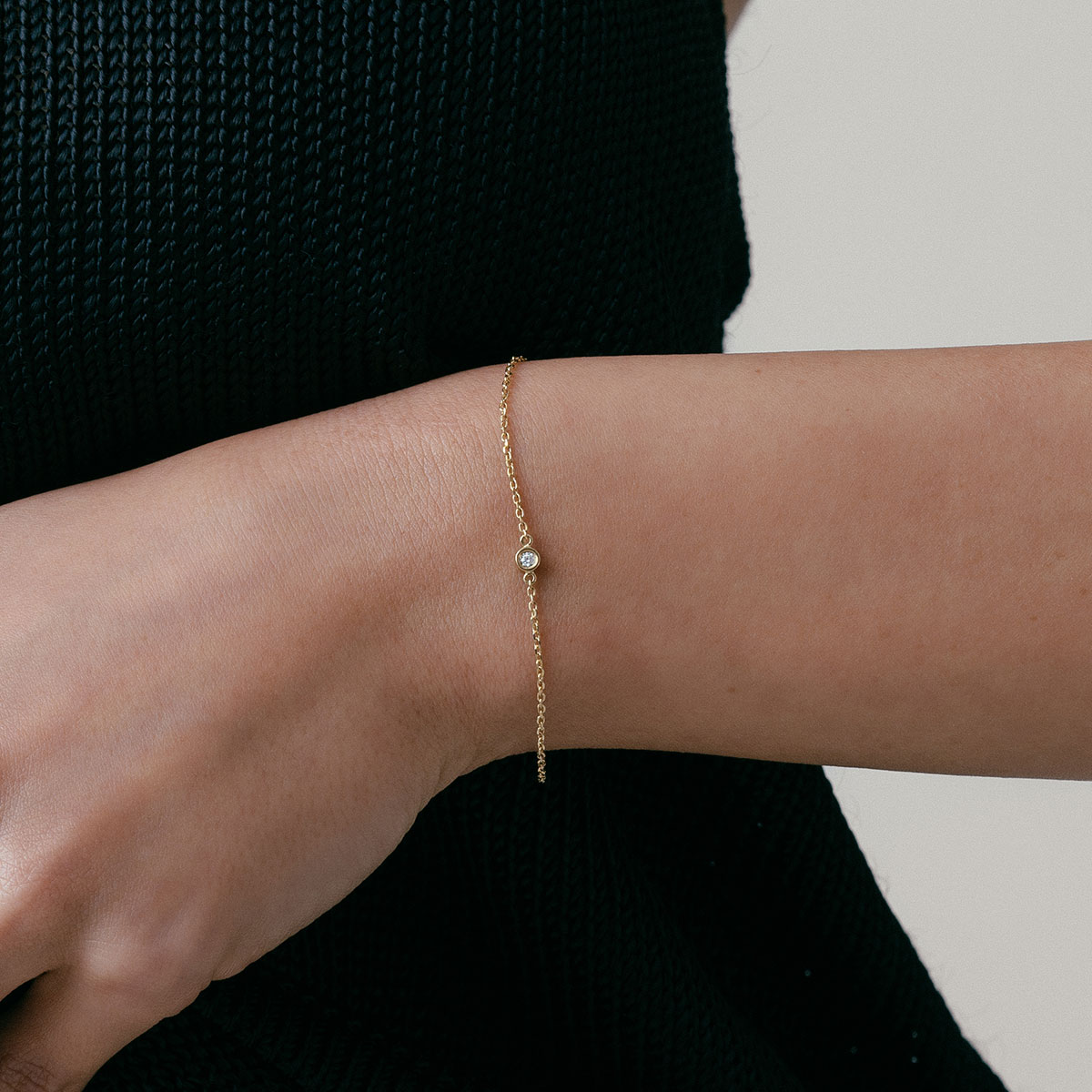 mulher usando pulseira minimalista feita à mão em ouro 18k com diamante ponto de luz central