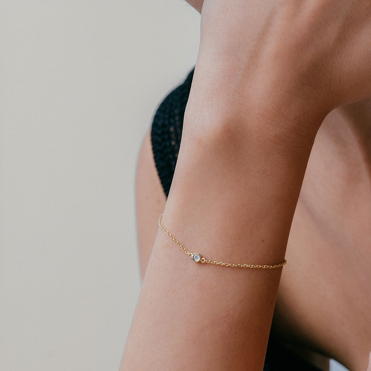 mulher usando pulseira minimalista feita à mão em ouro 18k com diamante ponto de luz central