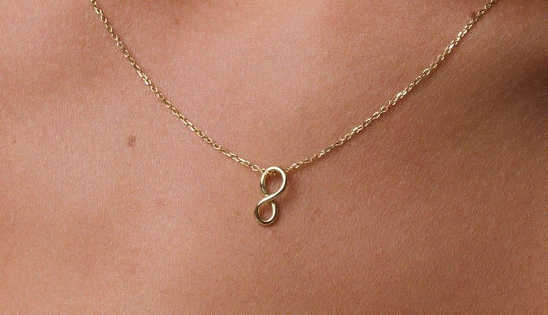 corrente com pingente infinito em ouro amarelo e diamantes no pescoço