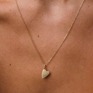 mulher usando um colar com pingente de coração com gravação personalizada de nome em ouro 18k