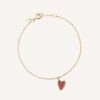 pulseira de ouro 18k com um pingente de coração cravejado com 14 rubis sobre fundo branco