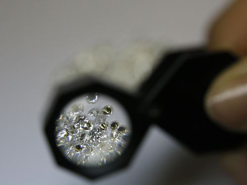 Diamantes sendo observados através de uma lupa de gemólogo durante processo de análise.
