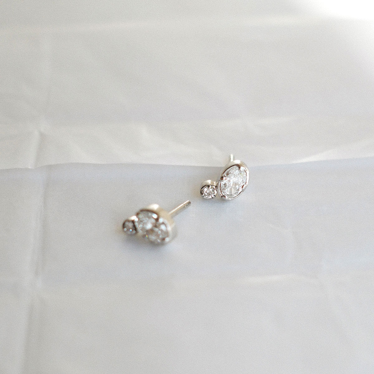 Brinco stud em ouro branco 18k com diamantes oval e redondo da Joias Liê.