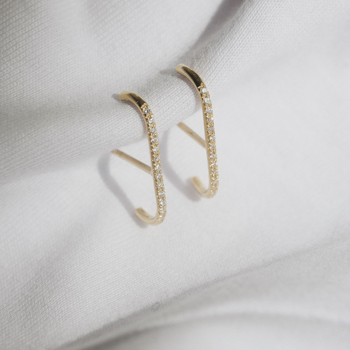 Fotografia still do Brinco traço em ouro amarelo 18k com diamantes, modelo delicado e curvado da Joias Liê, estilo ear cuff, que se encaixa no lóbulo.