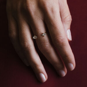 Mão usando anel aberto em ouro 18k com diamantes trillion e brilhante, joia minimalista da Joias Liê.