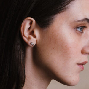 Mulher usando brinco em ouro 18k com diamantes oval e redondo, modelo Cecile da Joias Liê.