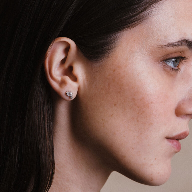 Mulher usando brinco em ouro 18k com diamantes oval e redondo, modelo Cecile da Joias Liê.
