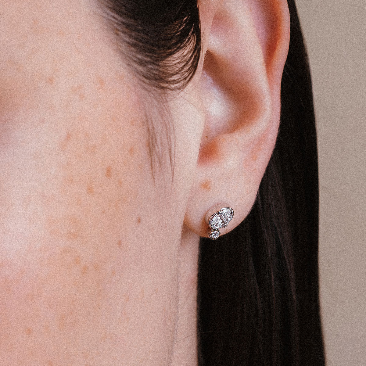 Mulher usando brinco em ouro 18k com diamantes oval e redondo, modelo Cecile da Joias Liê.