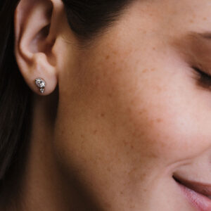 Mulher usando brinco em ouro 18k com diamantes oval e redondo, modelo Cecile da Joias Liê.