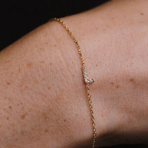 Pulso de mulher vestindo uma pulseira com a letra L, cravejada de diamantes lab grown, e corrente delicada em ouro 18k, modelo Pulseira Inicial com Diamantes da Joias Liê
