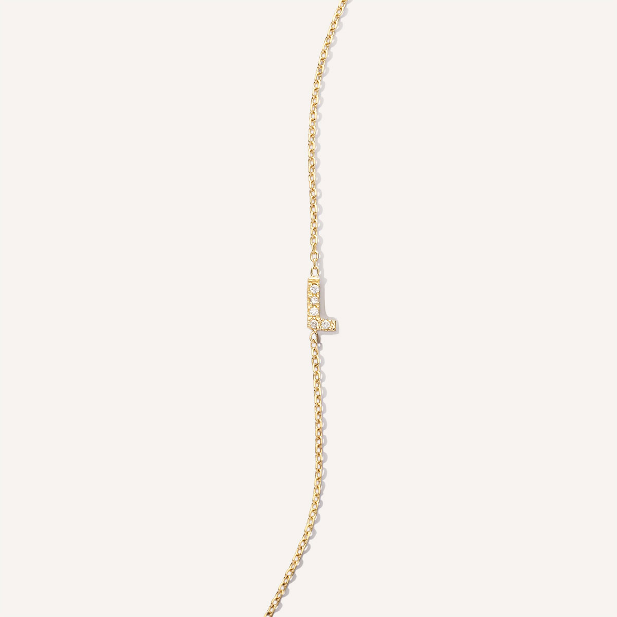 Pulseira de ouro 18k com inicial L cravejada com diamantes, da Joias Liê.