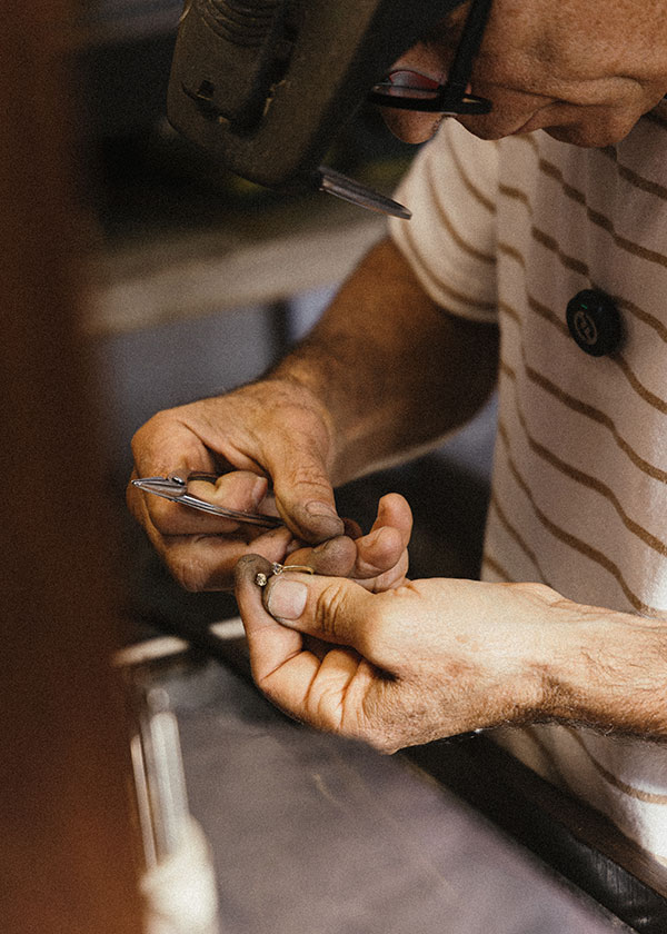 imagem de um ourives em sua banca fabricando um anel em ouro 18k e diamantes