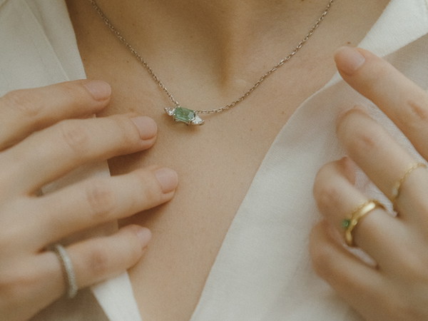 Mulher usando o Colar com Esmeralda e Diamantes Trillion da Liê Joias, peça sofisticada em ouro 18k com pedras preciosas.