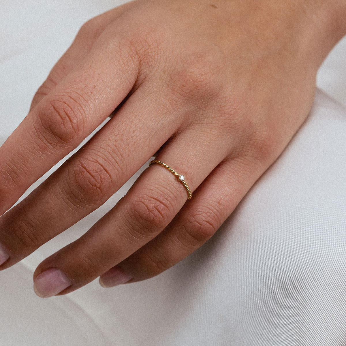Anel minimalista em ouro 18k com aro torcido e pequeno brilhante