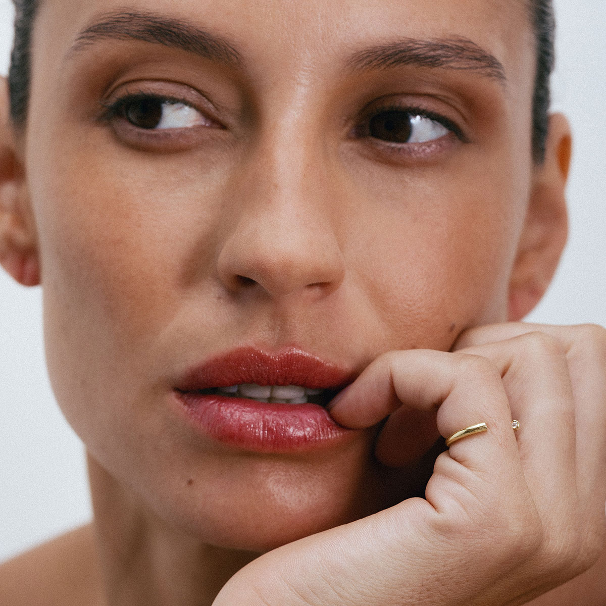 Anel minimalista aberto em ouro 18k com dois diamantes usado no dedo mindinho de uma mão feminina.