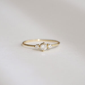 Anel minimalista em ouro 18k com um diamante central e dois diamantes laterais menores