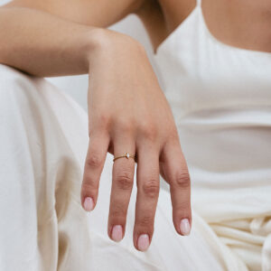 Anel com aro torcido em ouro 18k e diamante navete vestido em uma mão feminina