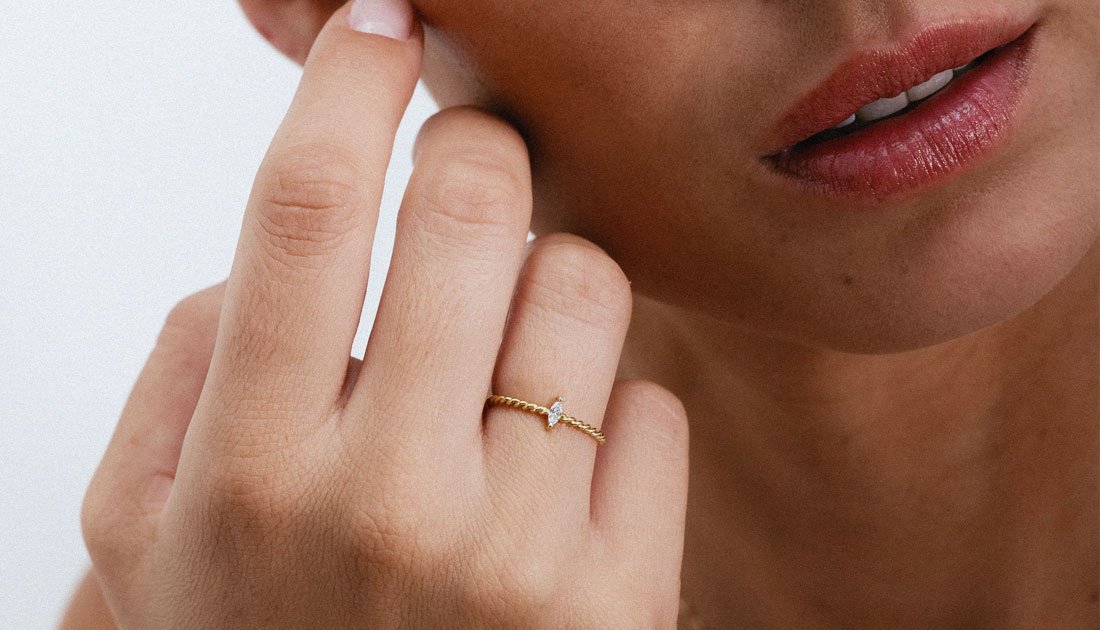 Anel com aro torcido em ouro 18k e diamante navete vestido em uma mão feminina