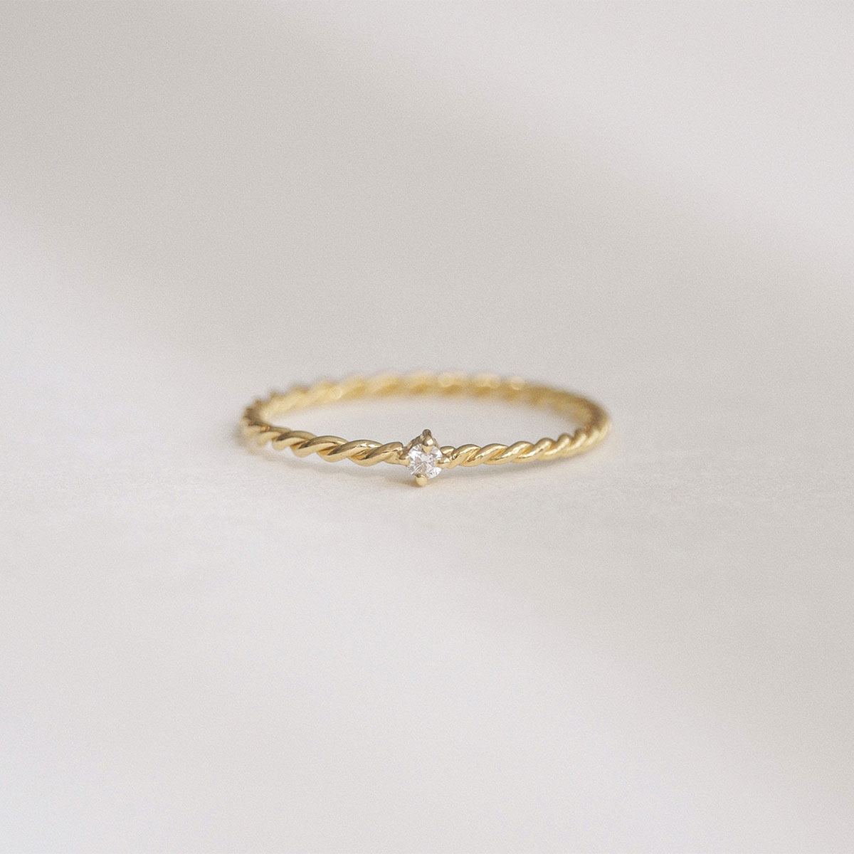 Anel minimalista em ouro 18k com aro torcido e brilhante pequeno