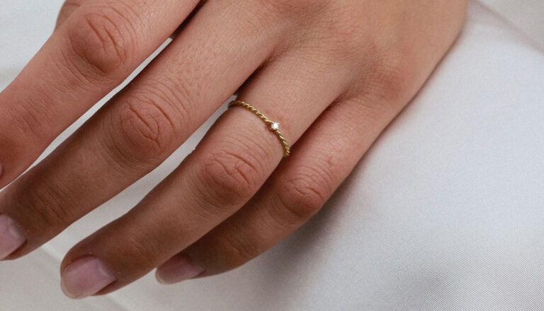 Anel com aro torcido em ouro 18k e diamante pequeno vestido em mão feminina