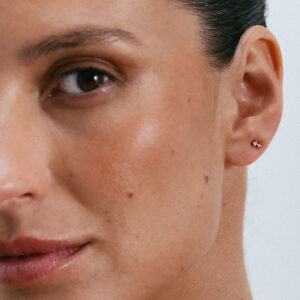 Brinco pequeno e delicado em ouro 18k com pequenos brilhantes vestido como piercing na orelha.