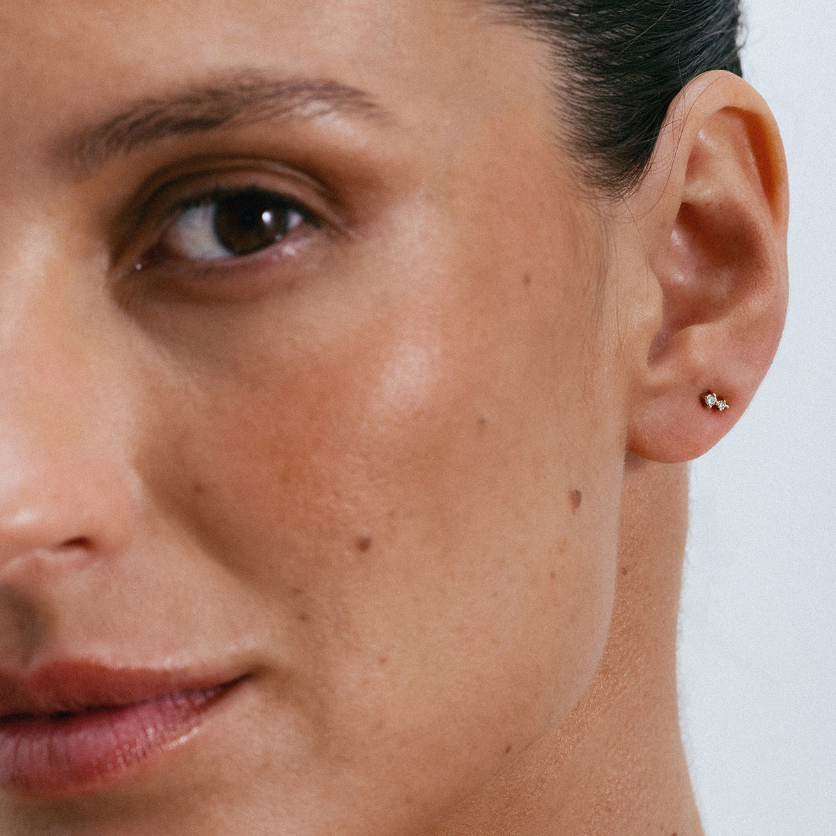 Brinco pequeno e delicado em ouro 18k com pequenos brilhantes vestido como piercing na orelha.