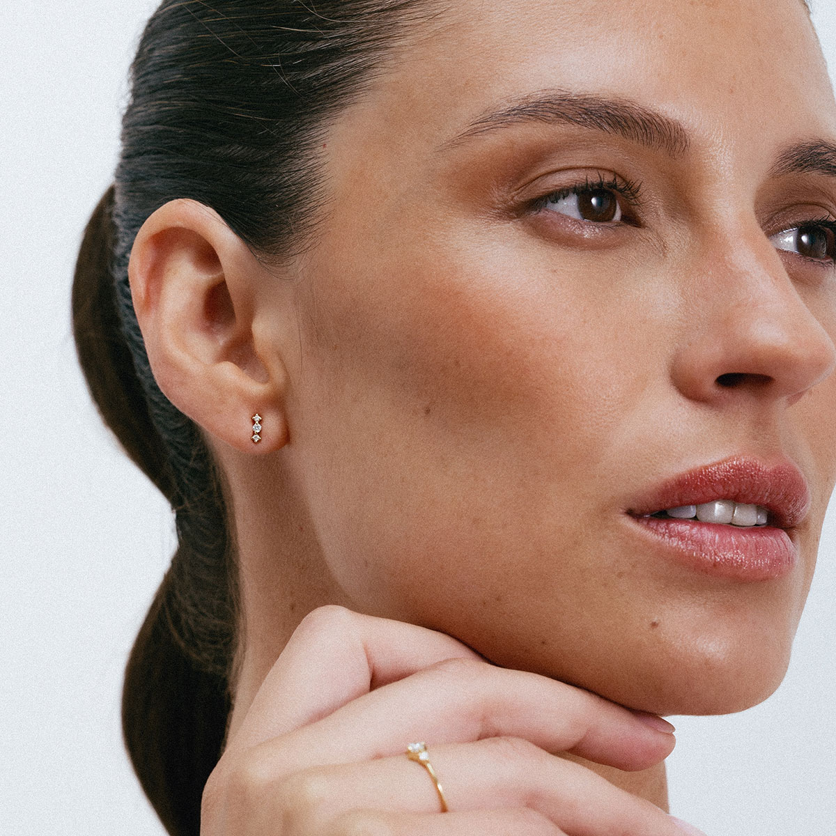 Brinco minimalista em ouro 18k com 3 pequenos diamantes vestido em orelha feminina